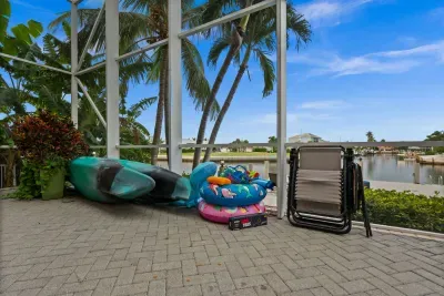 Screened waterfront patio with kayak, lounge chairs, and tropical canal views