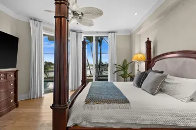 Elegant waterfront bedroom with four-poster bed and tropical views