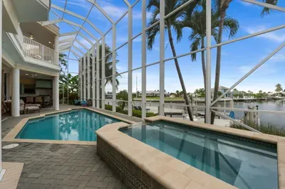 Screened waterfront pool & spa with serene tropical canal views