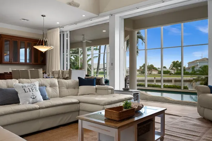 Bright waterfront living room with pool views and expansive glass doors