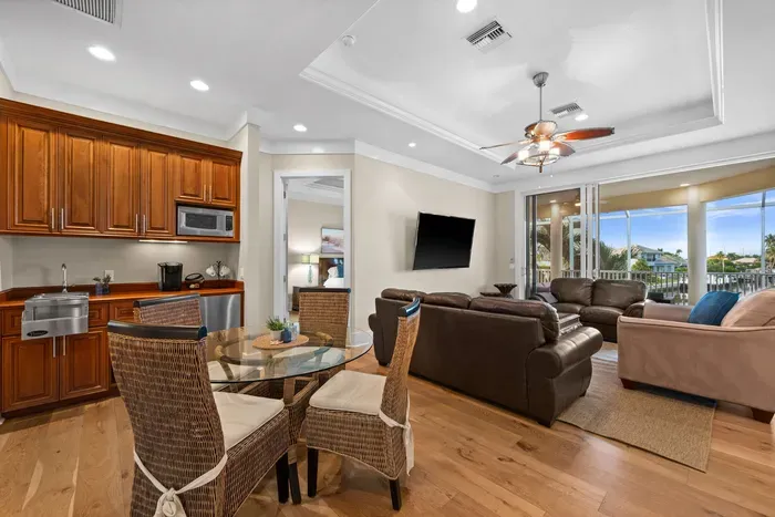 Bright waterfront living space with balcony, kitchenette, and cozy seating