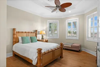 Bright bedroom with hardwood floors, plantation shutters & ceiling fan