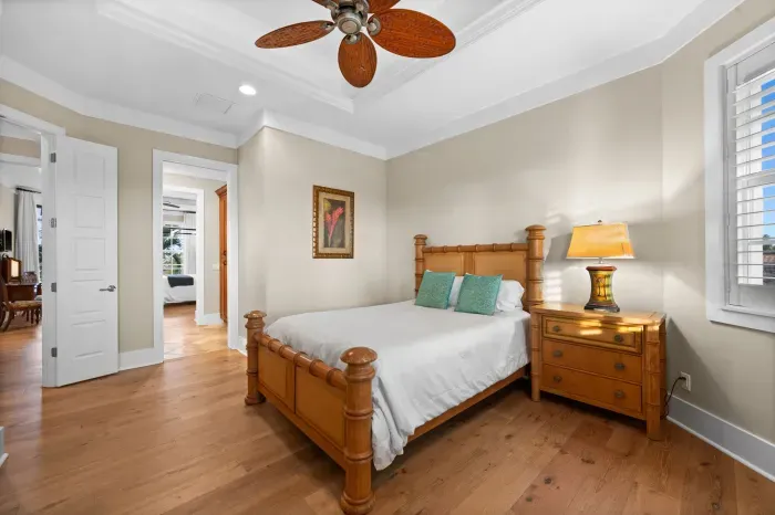 Bright coastal-style bedroom with hardwood floors and warm wood furnishings