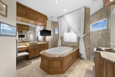 Spa-like luxury bath with soaking tub, elegant drapery, and warm finishes