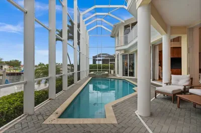 Private screened waterfront pool with covered lounge seating