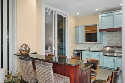 Covered outdoor kitchenette with grill, bar seating, and coastal-style cabinetry