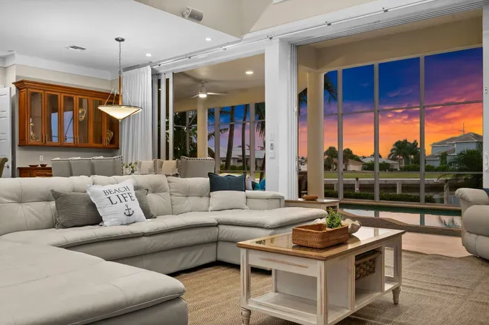 Spacious waterfront living room with sunset views and poolside access