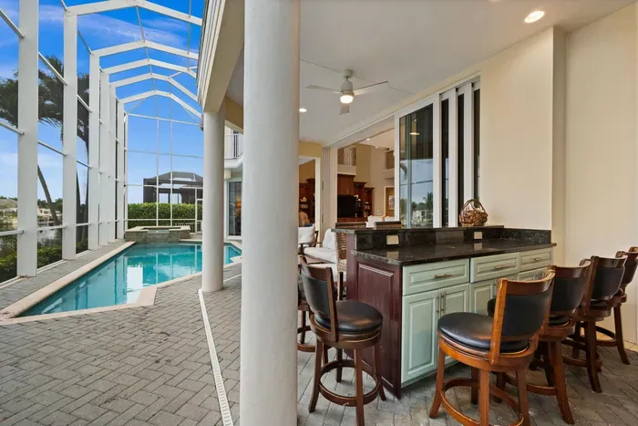 Private screened pool lanai with covered outdoor bar and resort-style seating