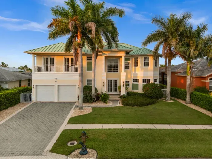 Elegant tropical home with palm-lined curb appeal and spacious driveway