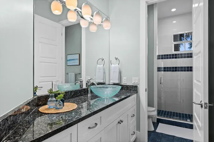 Bright modern bath with granite vanity and sleek walk-in shower