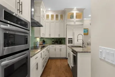 Bright gourmet kitchen with granite counters and elegant white cabinetry