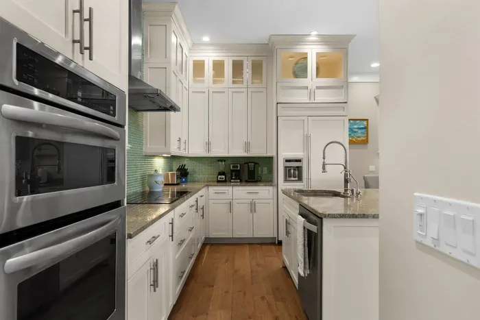 Bright gourmet kitchen with granite counters and elegant white cabinetry