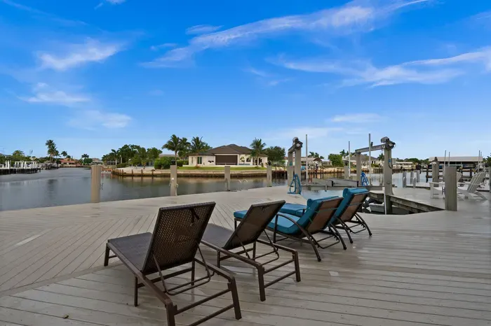 Spacious waterfront deck with lounge chairs, private dock, and canal views