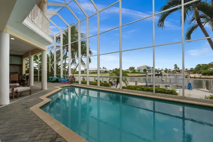 Screened waterfront pool with palm views and a relaxing covered lanai