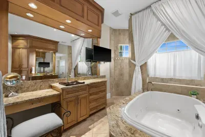 Spa-like bathroom with jetted soaking tub, granite vanity, and TV