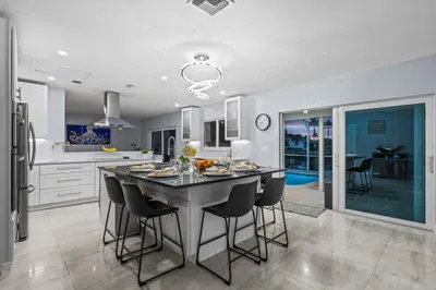 Modern chef’s kitchen with island seating and easy access to the pool