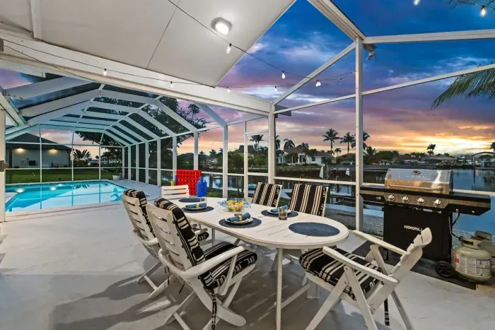 Screened waterfront lanai with pool views, grill, and sunset dining