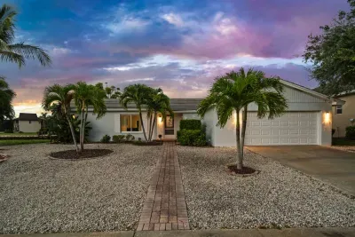 Tropical curb appeal with palm trees, garage, and glowing sunset views