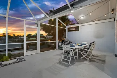 Screened waterfront lanai with sunset views and cozy outdoor dining