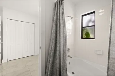 Bright full bathroom with tub-shower combo and natural light