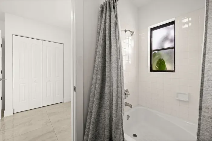 Bright full bathroom with tub-shower combo and natural light