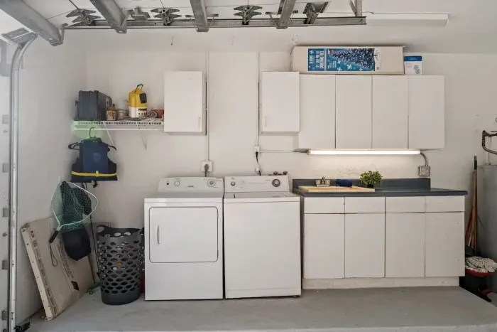 Convenient garage laundry area with storage cabinets and utility sink