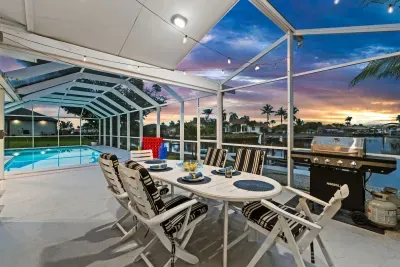 Screened waterfront lanai with pool views, grill, and sunset dining