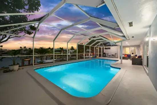Screened waterfront pool oasis with sunset views and covered patio seating