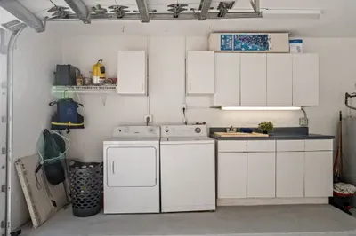 Convenient garage laundry area with storage cabinets and utility sink