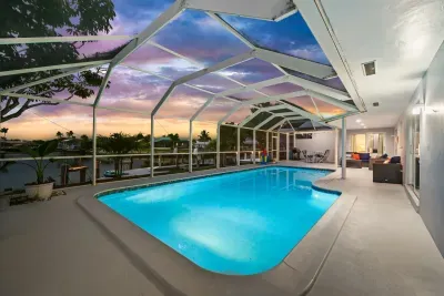 Screened waterfront pool oasis with sunset views and covered patio seating