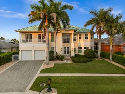 Grand tropical home with palm-lined curb appeal and elegant entrance