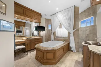 Spa-style bathroom with soaking tub, granite vanities, and elegant finishes