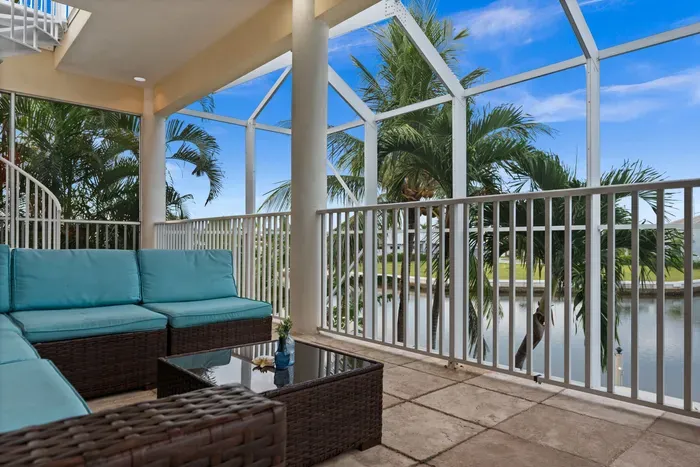 Screened waterfront lanai with comfy seating and tropical canal views