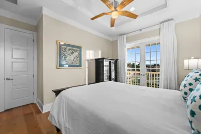 Bright coastal bedroom with French doors and private balcony views