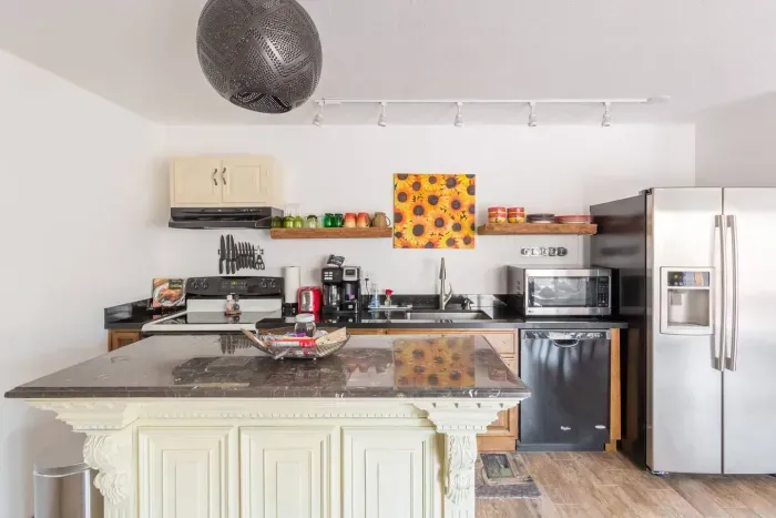 Fully stocked kitchen area with microwave, full sized refrigerator dishwasher, stove, coffee maker, and cookware.