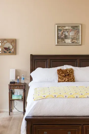 Bed, nightstand, flower, and complimentary bottled water.
