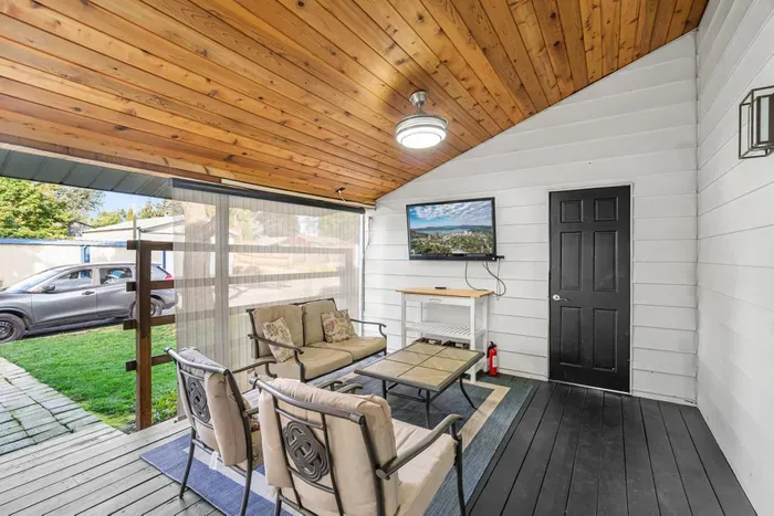 Cozy covered patio with cushioned seating and outdoor TV