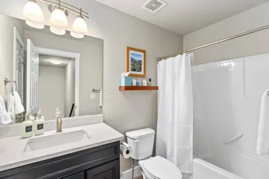 SECONDARY BATHROOM: Shower-tub combo, toiletries, and amenities.
