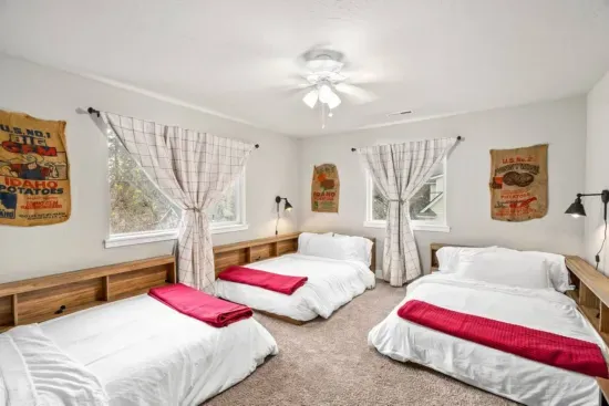 BEDROOM 4: Three full-size beds, nightstand with lamp, phone charger, room-darkening curtains, luggage rack, ceiling fan, clothes hamper, closet with hangers, desk, and chair.