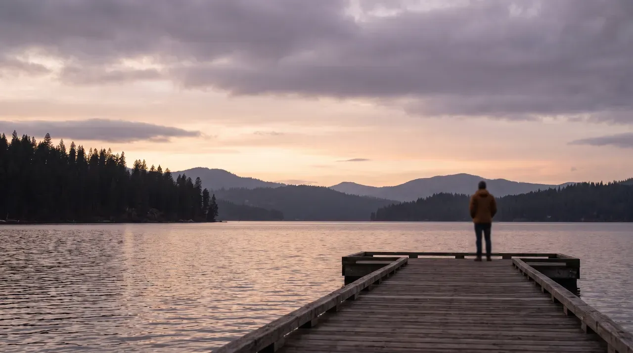 Person on a dock overlooking a lake at sunset