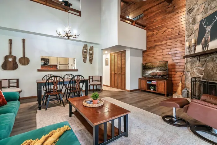 Open concept family room with electric fireplace, large TV, access to balcony and dining table.