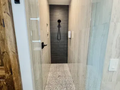An oversized shower in the second primary bathroom features floor-to-ceiling tile and all the necessary amenities – shampoo, conditioner, and body wash – for a luxurious experience.