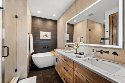 A luxurious primary bathroom with ample space for both to get ready. Enjoy a full-size soaking tub, oversized shower, floor-to-ceiling designer tile, and a lighted mirror with a built-in Bluetooth speaker and weather station to kickstart your day.