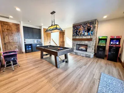 Spacious game room featuring a 7' pool table, Ms. Pac-Man, NBA Jam, and Golden Tee Golf 3D. Enjoy a 75" Smart Roku TV and a cozy gas fireplace for family fun.