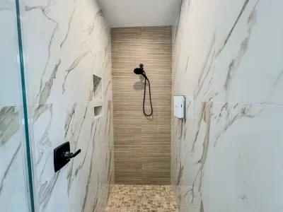 Oversized shower in the primary bathroom featuring floor-to-ceiling tile and all the necessary amenities – shampoo, conditioner, and body wash – for a luxurious experience.