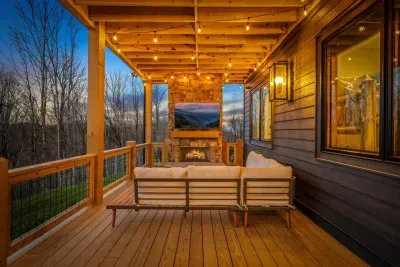 The lower deck offers comfortable sofas for relaxing while watching the 75" smart TV, with a cozy gas fireplace to keep you warm. String lights add the perfect touch, creating a relaxed atmosphere.