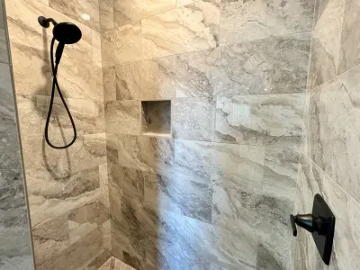 The walk-in shower features floor-to-ceiling tile and all the necessary amenities – shampoo, conditioner, and body wash – for a luxurious experience.
