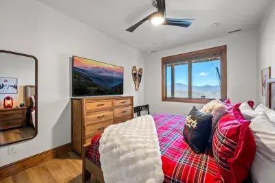 A large window offers a beautiful view of the Blue Ridge Mountains.  There is also a 65" Smart TV,  large dresser and 2 night stands for plenty of space. This bedroom is a perfect blend of rustic charm and alpine adventure.