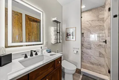 The ski-themed bathroom perfectly blends elegance with adventure.  The walk-in shower features a sleek glass door and modern fixtures.  Plush, large white towels are provided for guests, as well as washcloths and hand towels.