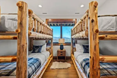 This cozy bunk room offers a perfect escape into nature. The space exudes rustic charm with bunkbeds made from sturdy, weathered timber adorned with soft plaid bedding, inviting guests to unwind after a day of exploring.